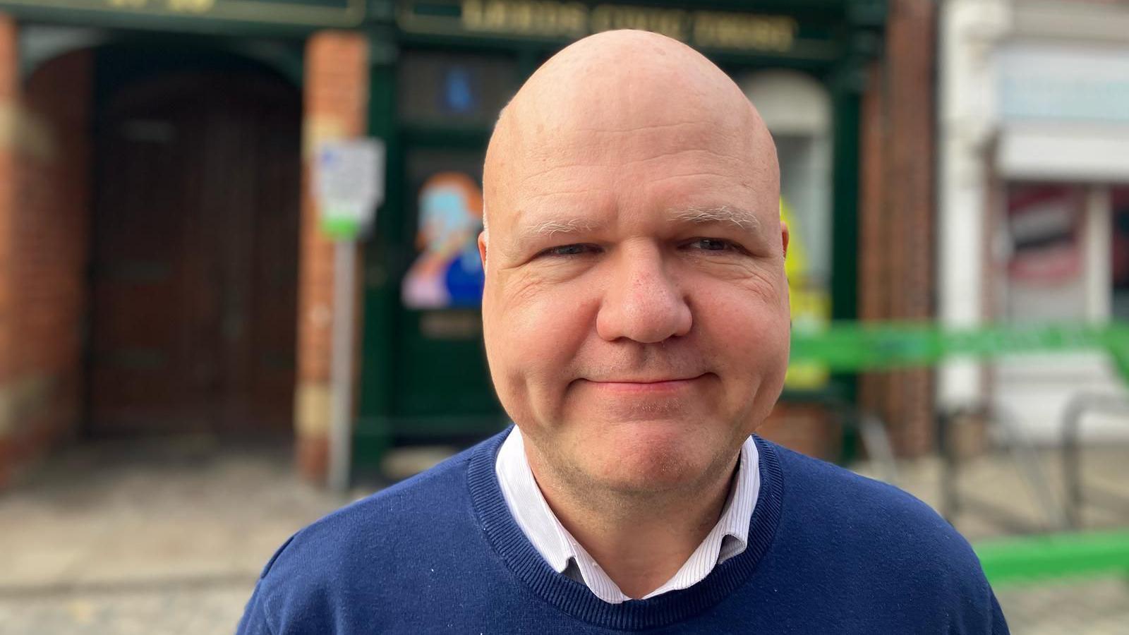 The Director of Leeds Civic Trust, Martin Hamilton, smiles for the camera wearing a blue jumper in front of the Leeds Civic Trust offices.