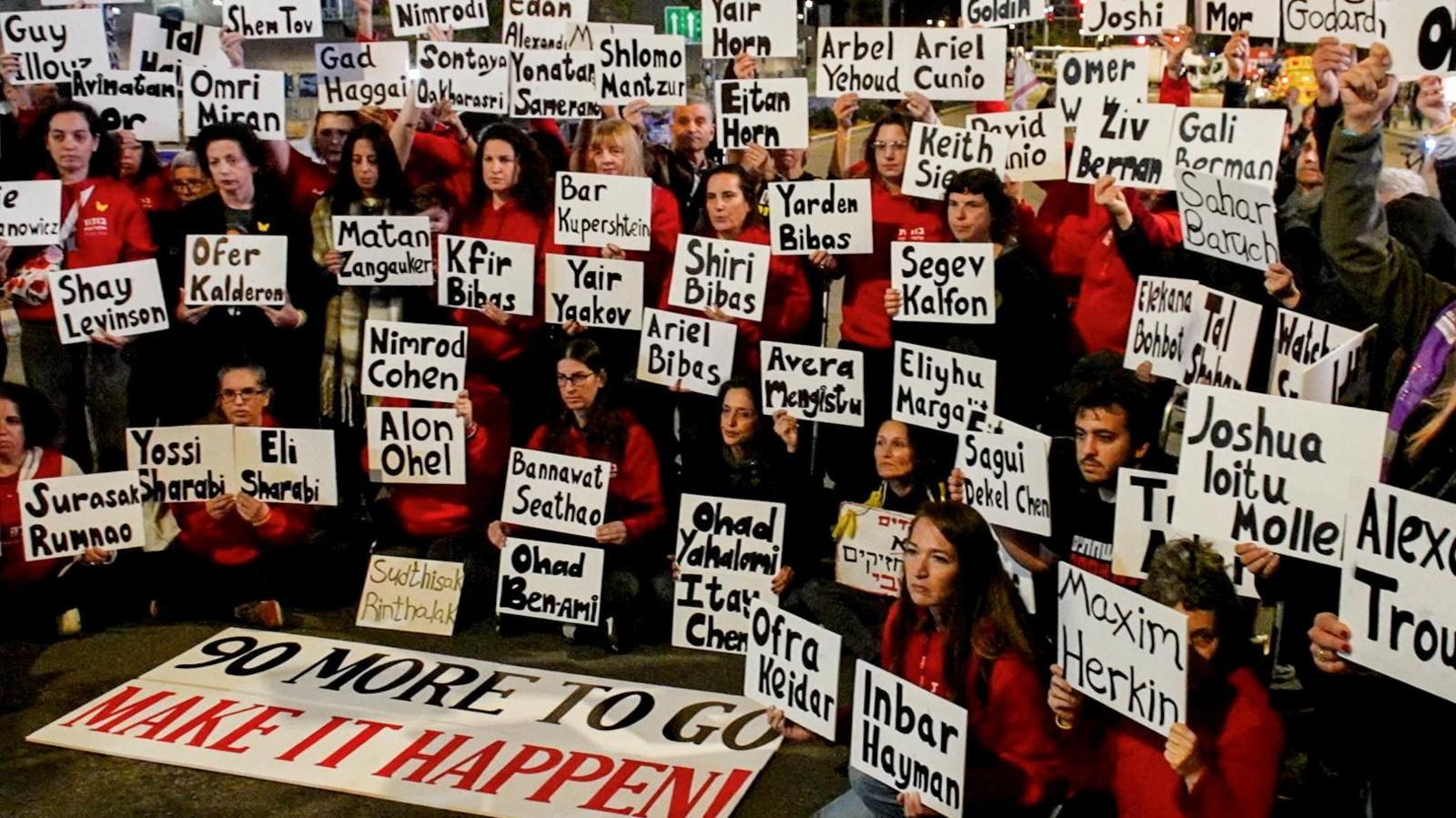 Israelis carry signs bearing the names of the remaining hostages held by Hamas in Gaza, at a protest in Tel Aviv, Israel (25 January 2025). A sign on the ground at the front says "90 more to go, make it happen"