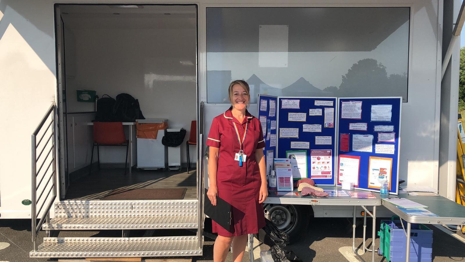 A staff member stands outside a van