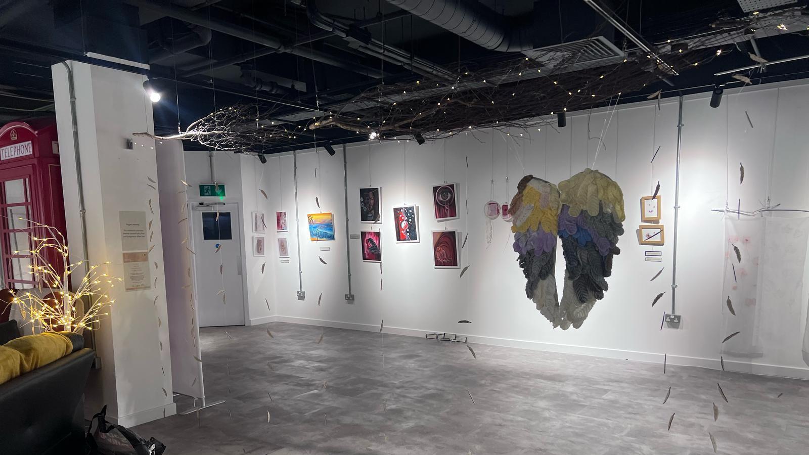 Art displayed on walls as well as a knitted set of wings hanging from the roof