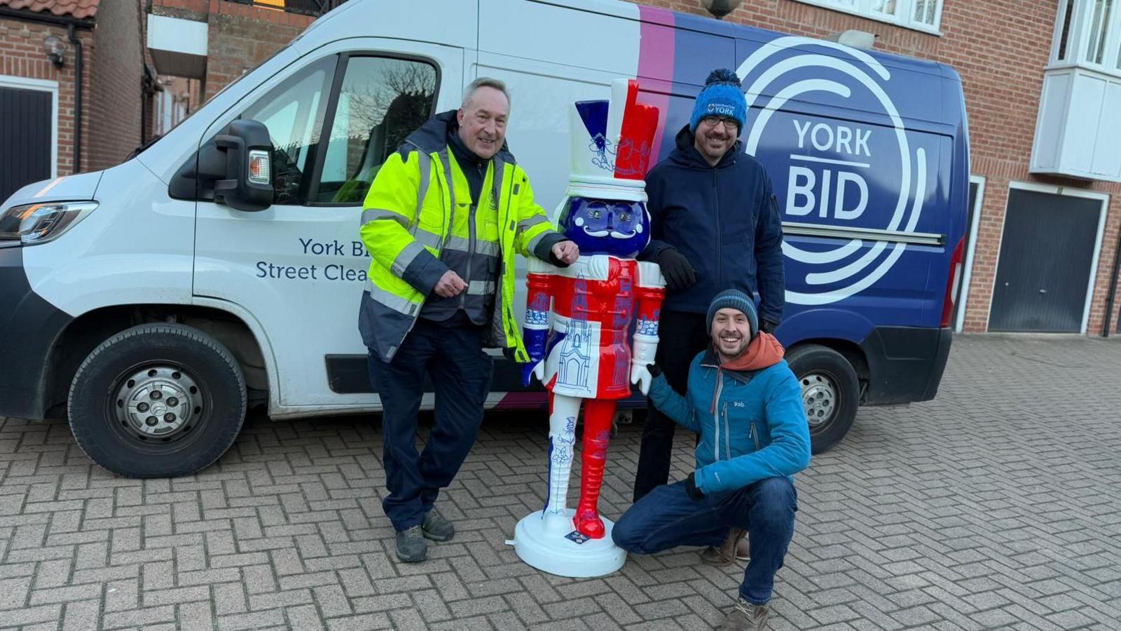 Great Britain-themed Nutcracker statue, decorated with Union Flag, with three people and a York BID-branded van