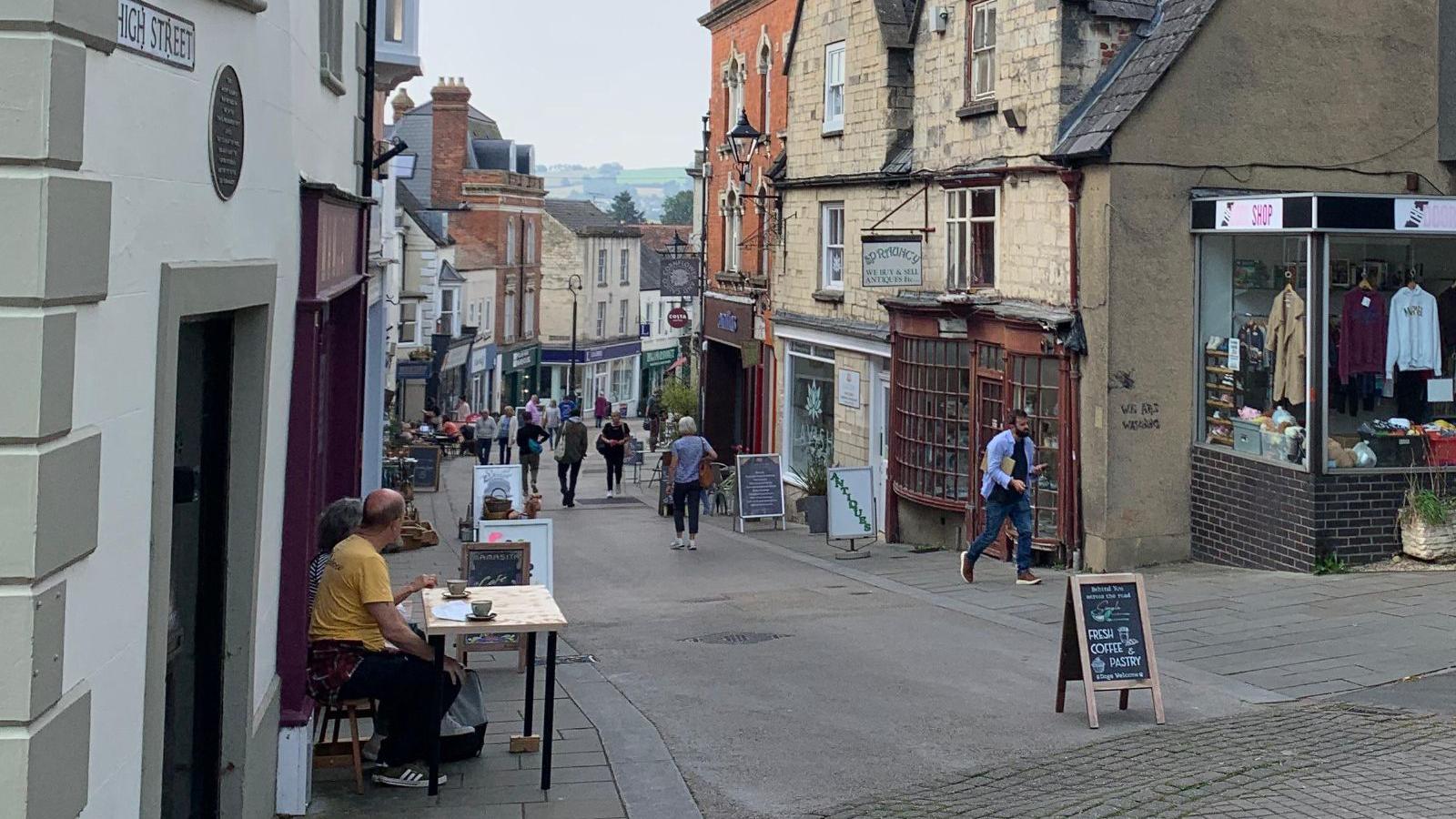 Image shows people walking up and down Stroud high street. 