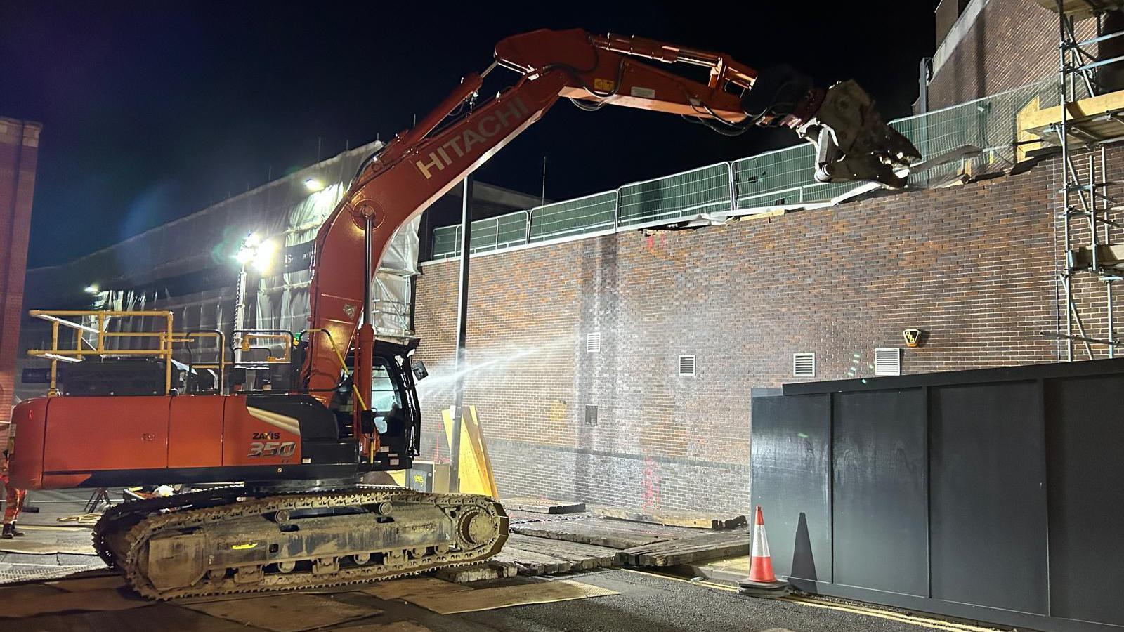 Heavy machinery being used to knock down an external wall