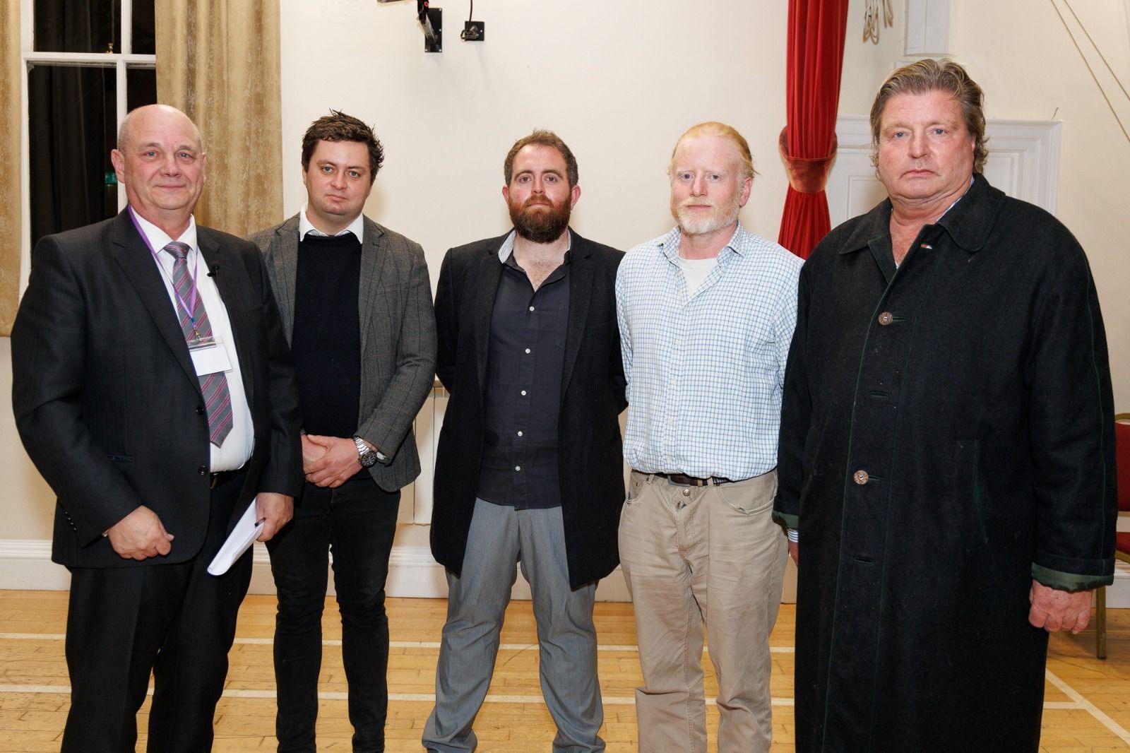 5 men stood posing for a photo in Alderney’s town hall. All in formal wear. From left to right,  Returning officer Theo Leisjer, Alex Snowdon, Iain Macfarlane, Stuart Clark, Edward Hill