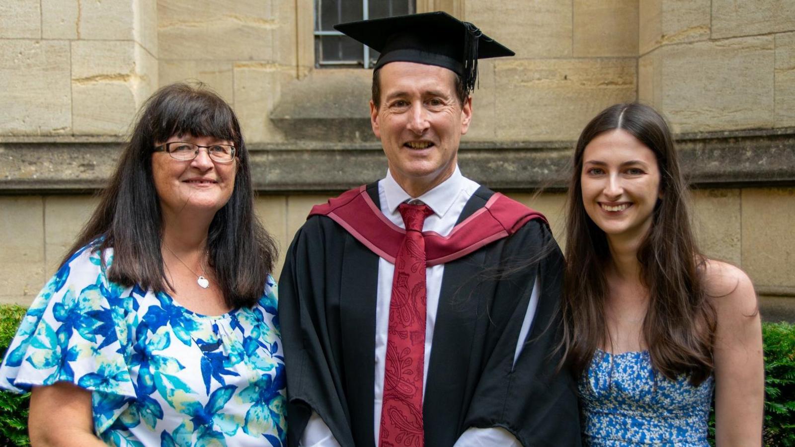 Mathew standing between his wife and daughter