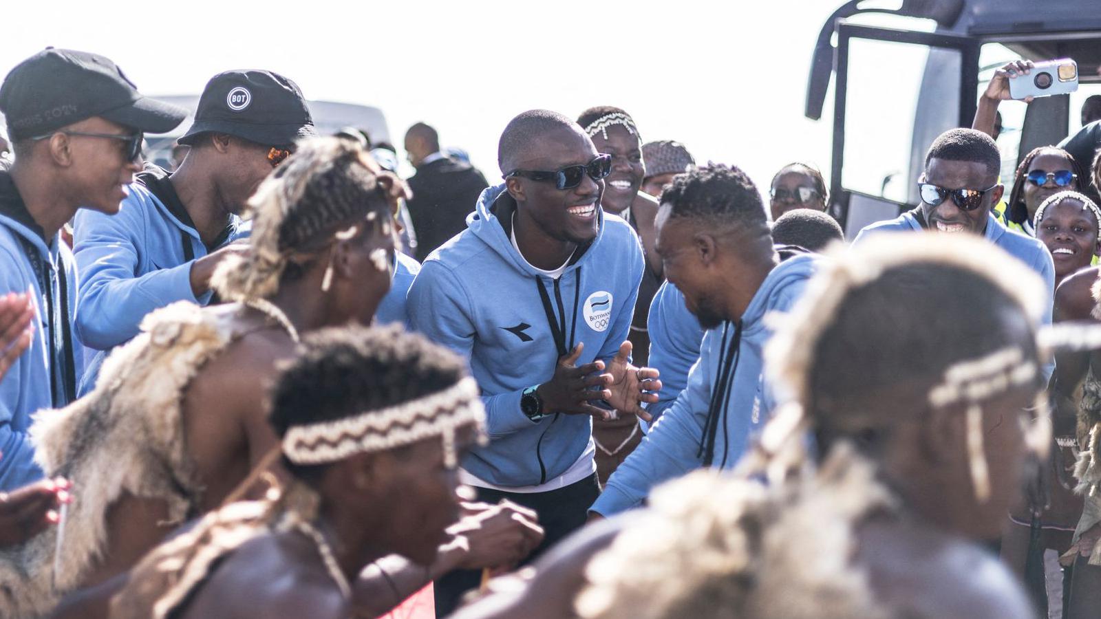 Olympic gold medallist Letsile Tebogo (C) and other members of Team Botswana dance with a cultural group during a welcoming ceremony after winning the men's 200m athletics event during the Paris 2024 Olympic Games