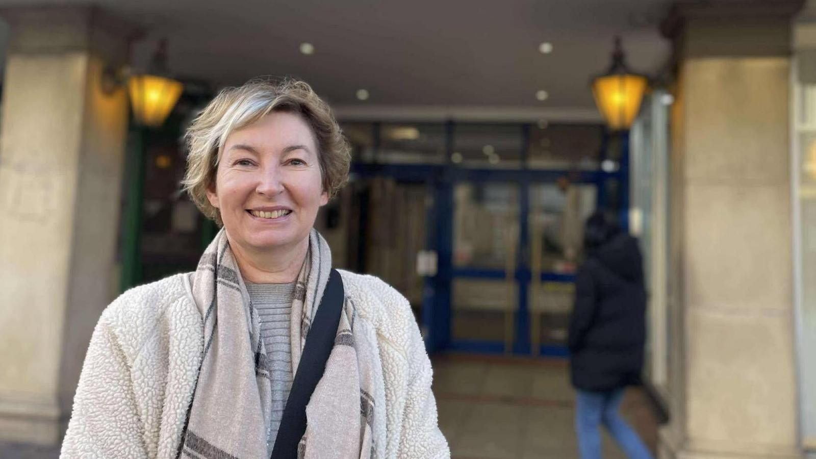 A woman in a warm fleece and scarf stood outside the centre