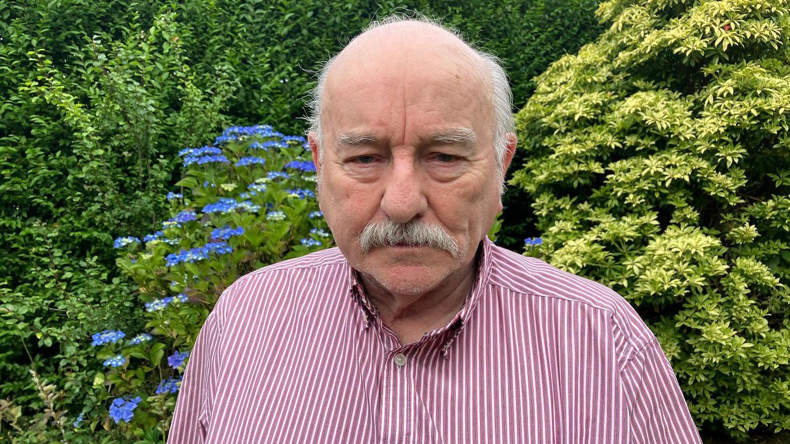 Eddie Mahon stares into the camera in a stripey shirt 