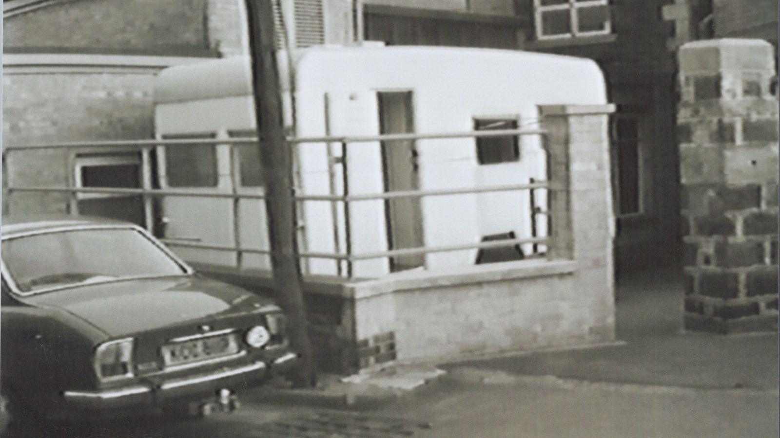 Llun du a gwyn o garafan a char tu allan i adeilad