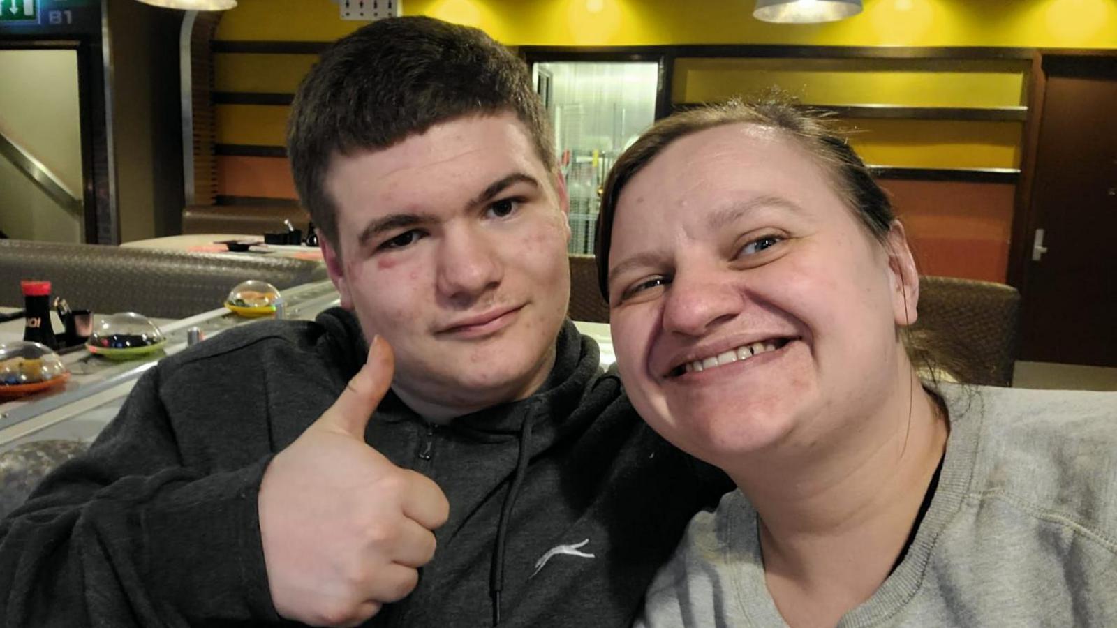 A selfie of Sarah Sissons wearing a grey sweatshirt with her son Ryan, holding a thumbs-up pose and wearing a grey hoody