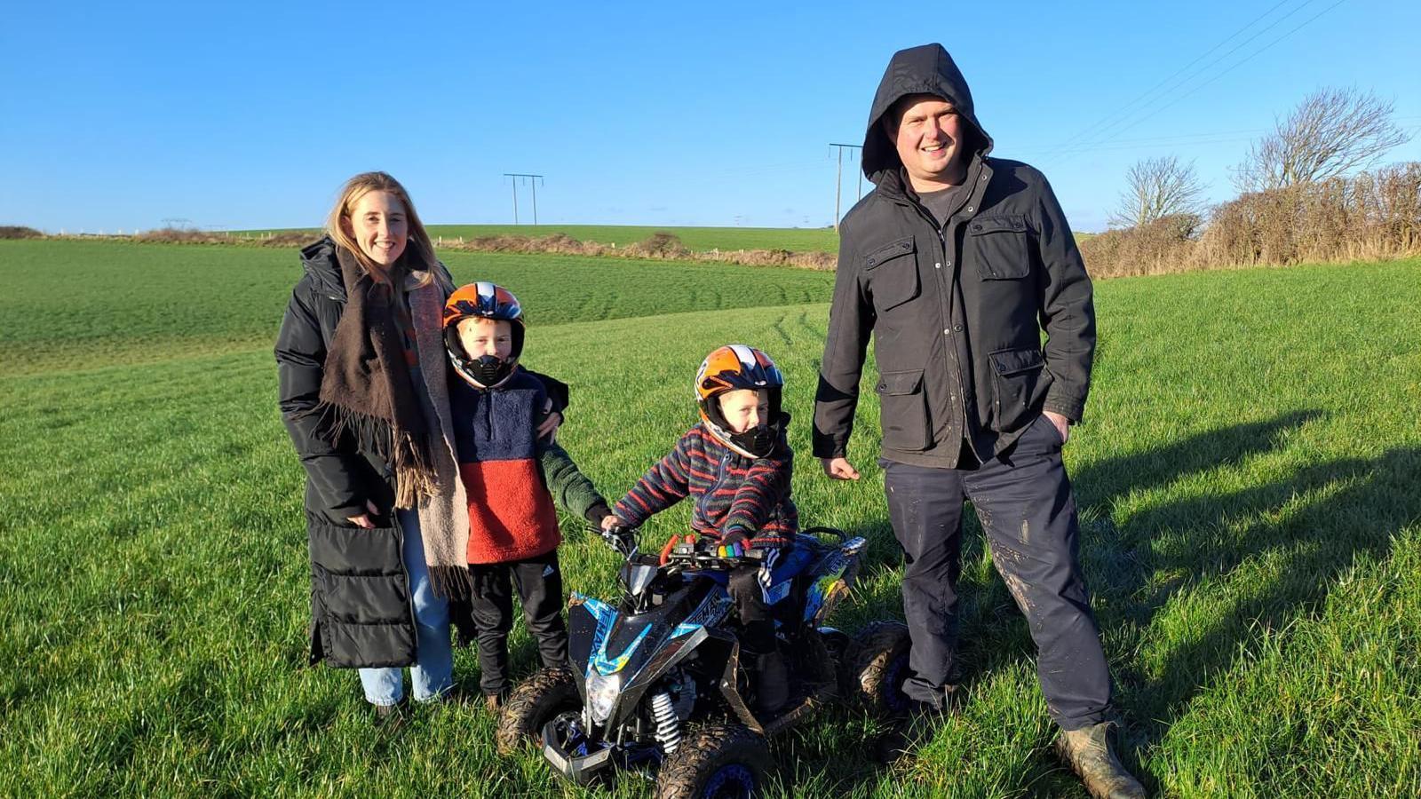 Llun o deulu, mam, dad a dau fab ifanc.