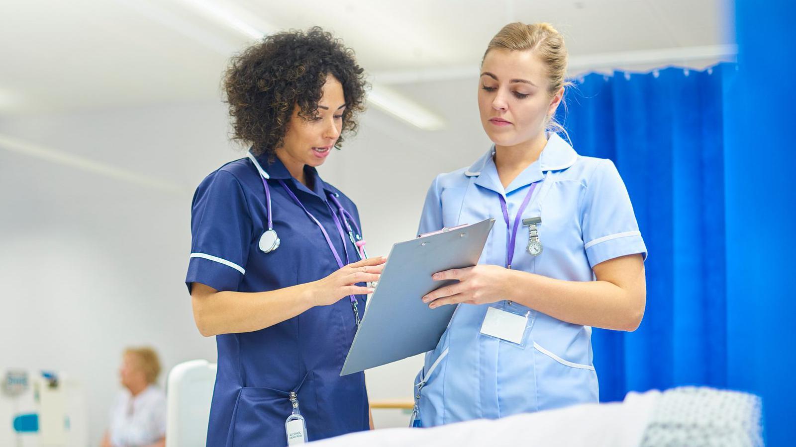 Two nurses speaking to each other in a hospital