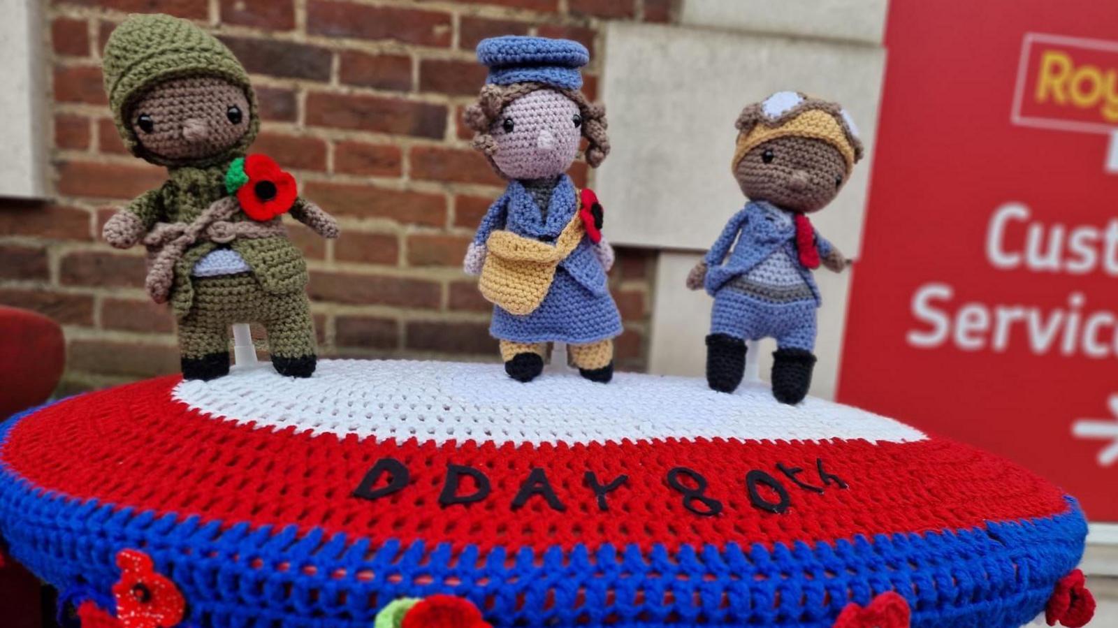 A postbox topper by the group, featuring three figures from World War Two, including a soldier and a postal worker. All are wearing poppies 