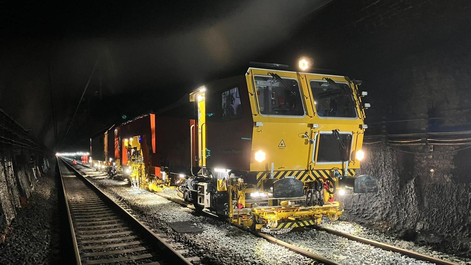 A tamping machine compacting stone in a railway tunnel