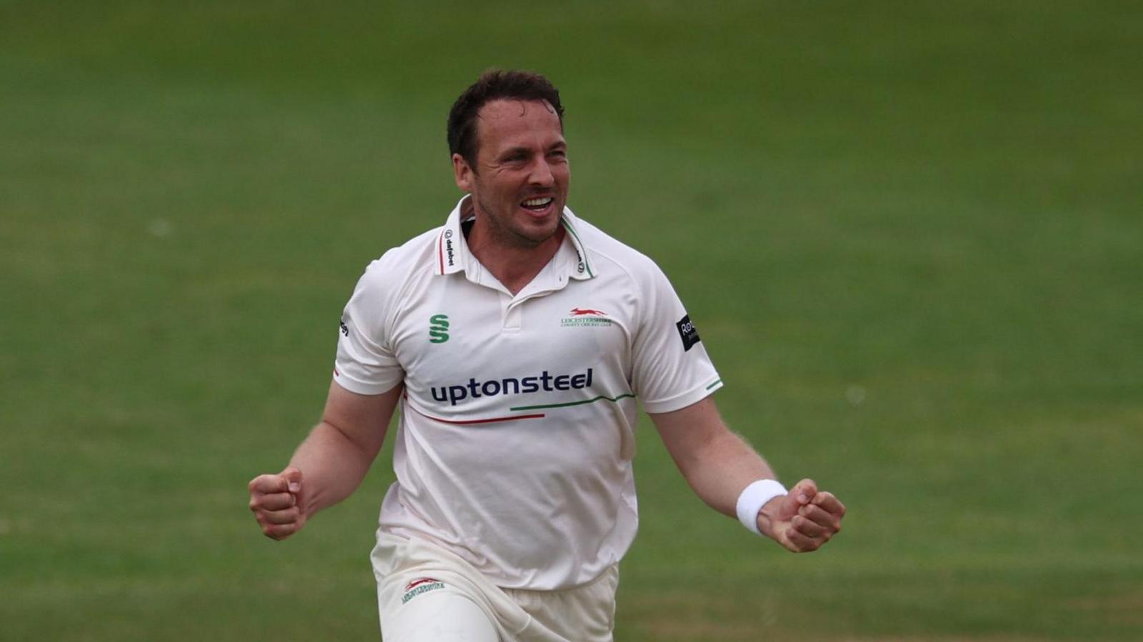 Leicestershire bowler Josh Davey celebrating taking a wicket with his arms out wide, clenching his fists.