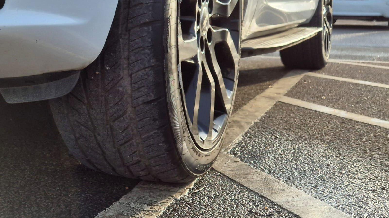 A car parked with two wheels on the white line at the side of the parking space