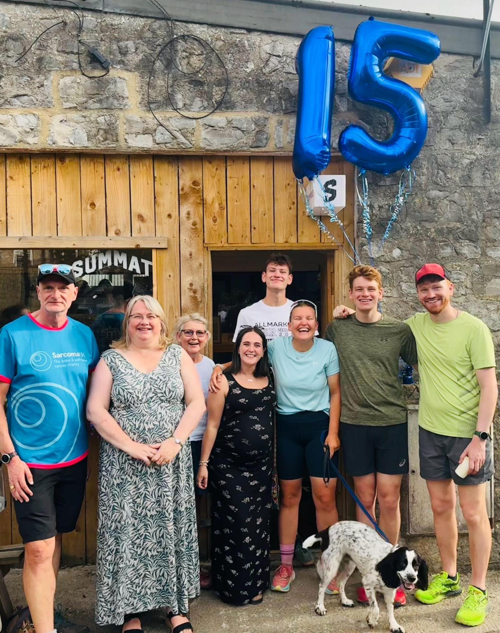 A number of family and friends around Dr Pragnell with a 15 balloon above them.