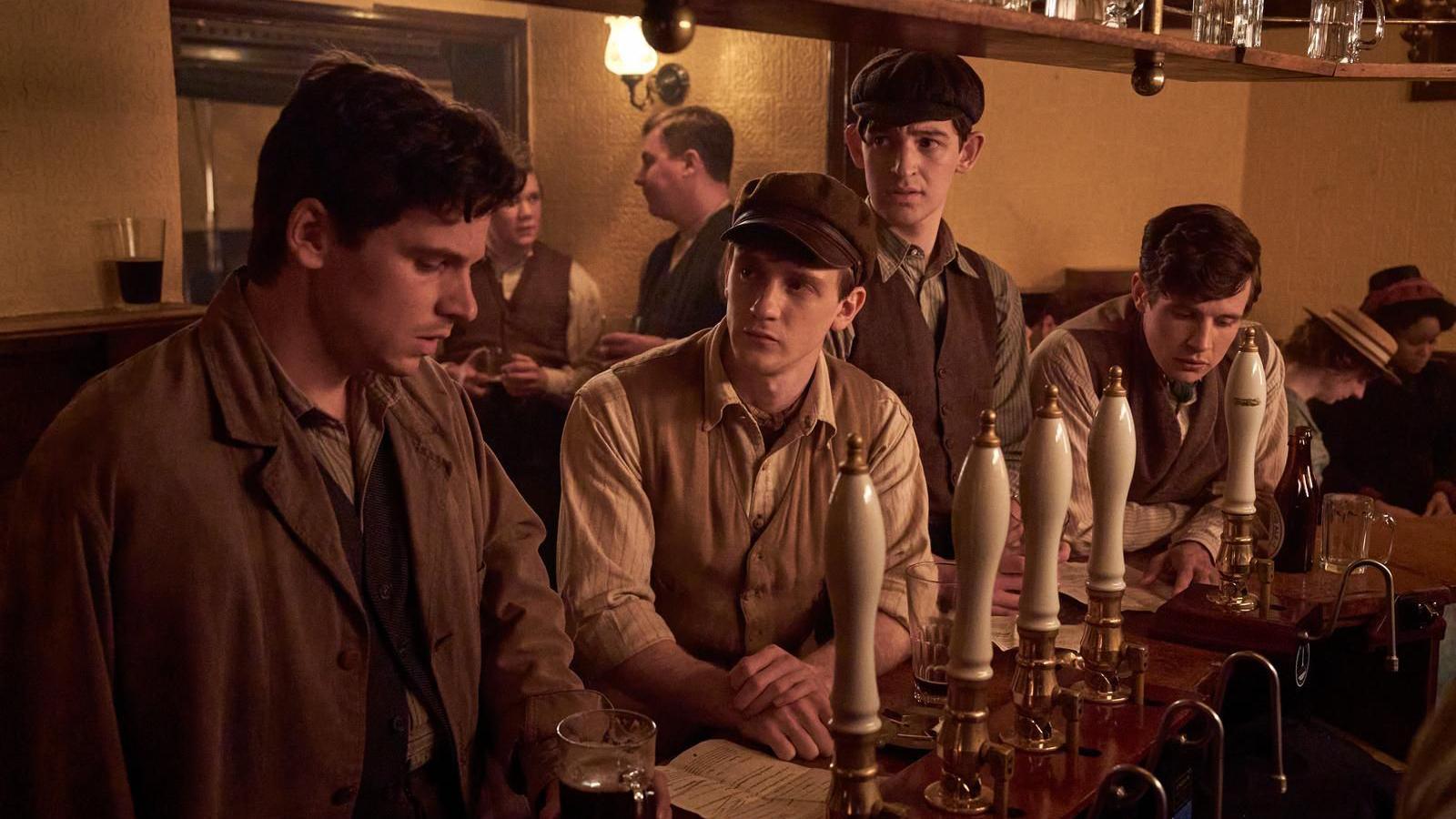 A screengrab from The Choral, featuring four people standing in a wartime bar.