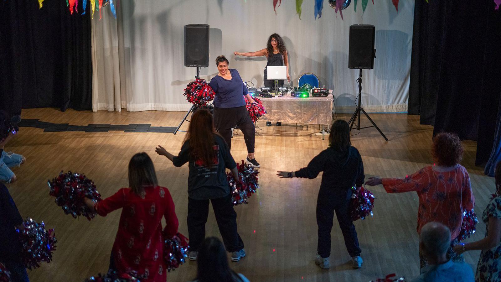 Women holdings pom-poms dancing to Bollywood-themed music 