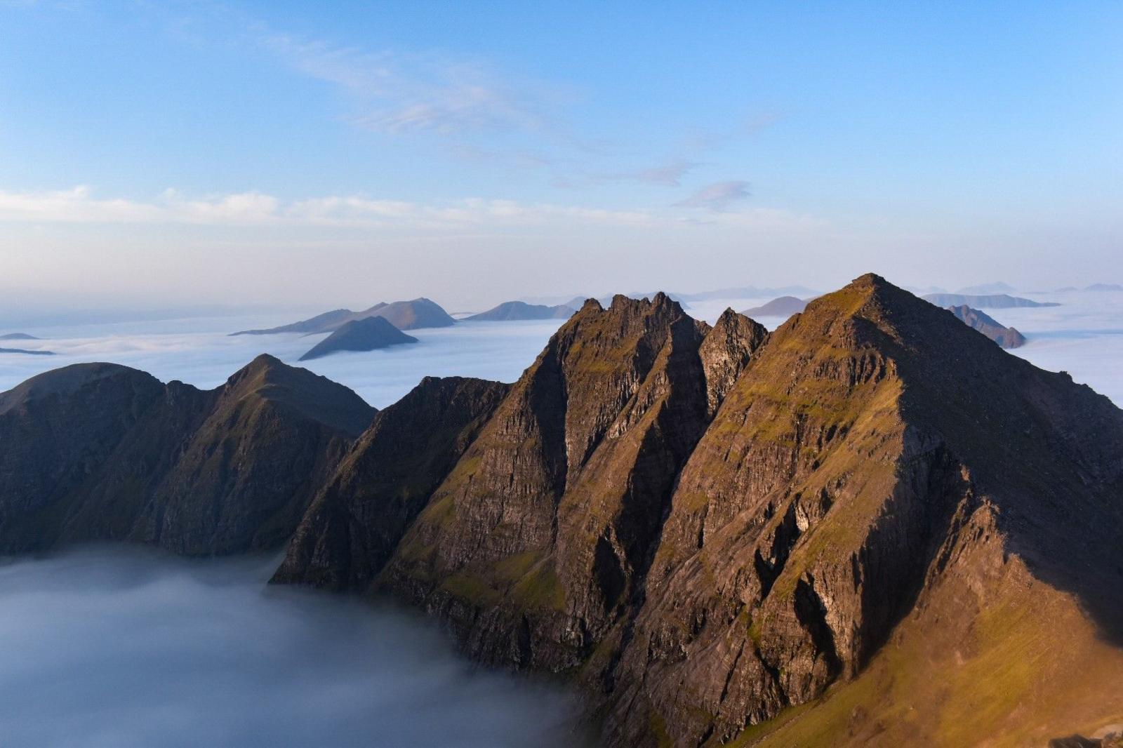 A string of mountain tops just out from above a misty sky