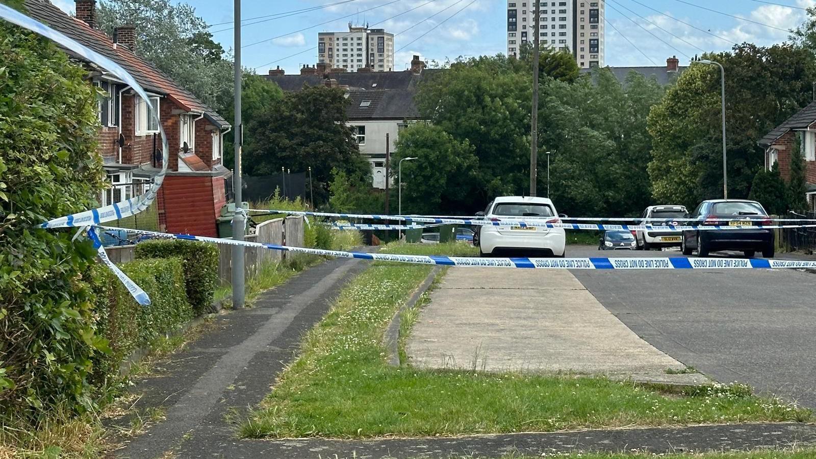 Police tape outside a house, cordoning off a pavement.