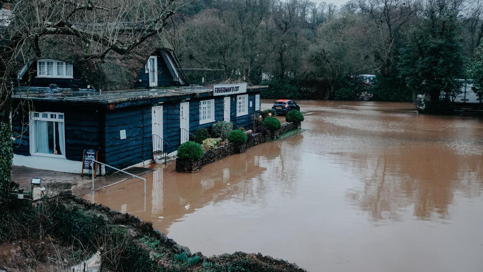 Brown floodwater covers a car park to a restaurant