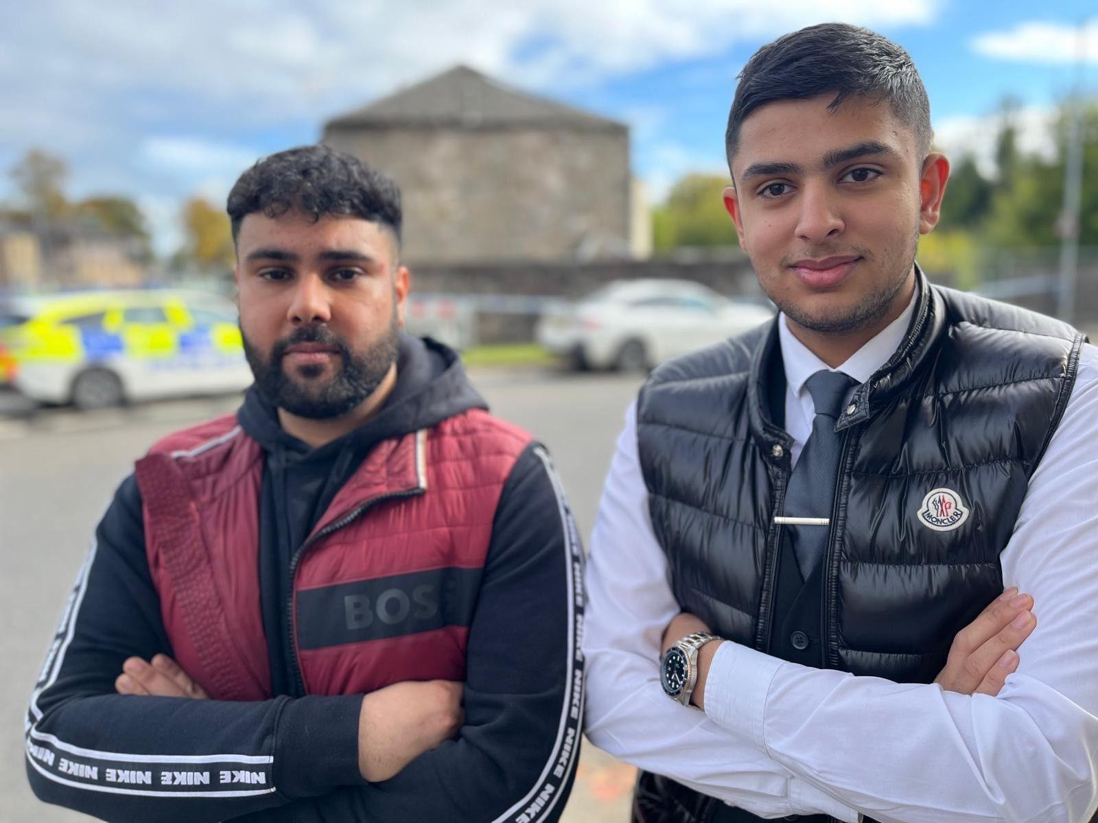 Two young men with arms crossed standing in a street looking at the camera