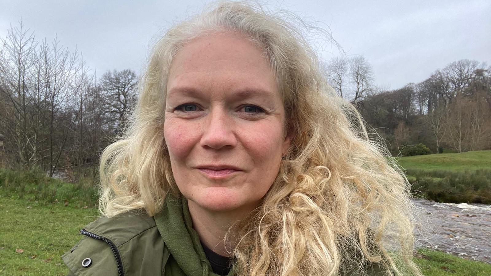 Gynaecology patient Pippa, smiles in a photo outdoors in the countryside.