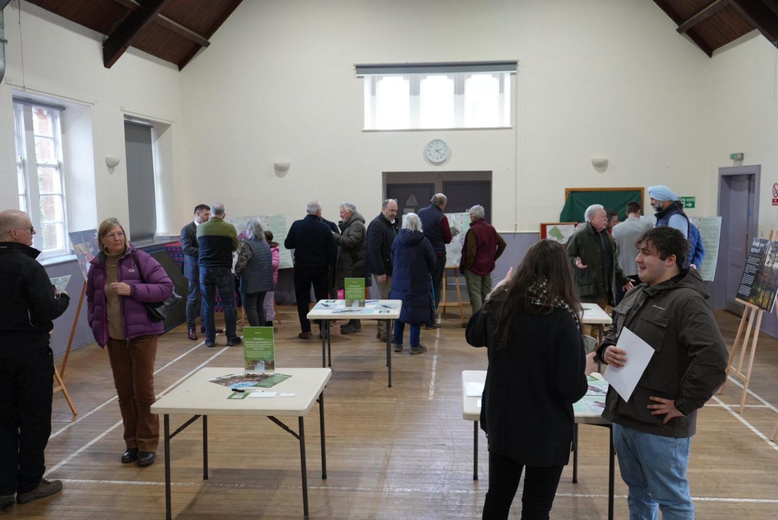 A public consultation event with tables and displays of Center Parcs plans for the Borders with people looking them over