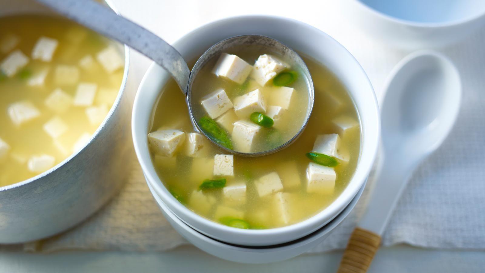 A saucepan of miso soup and a small bowl of it (right). There's a ladel adding soup to the bowl. 