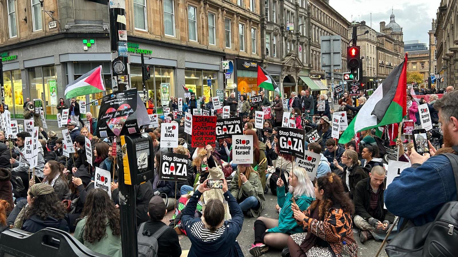 A crowd of people carrying signs and Palestinian flags