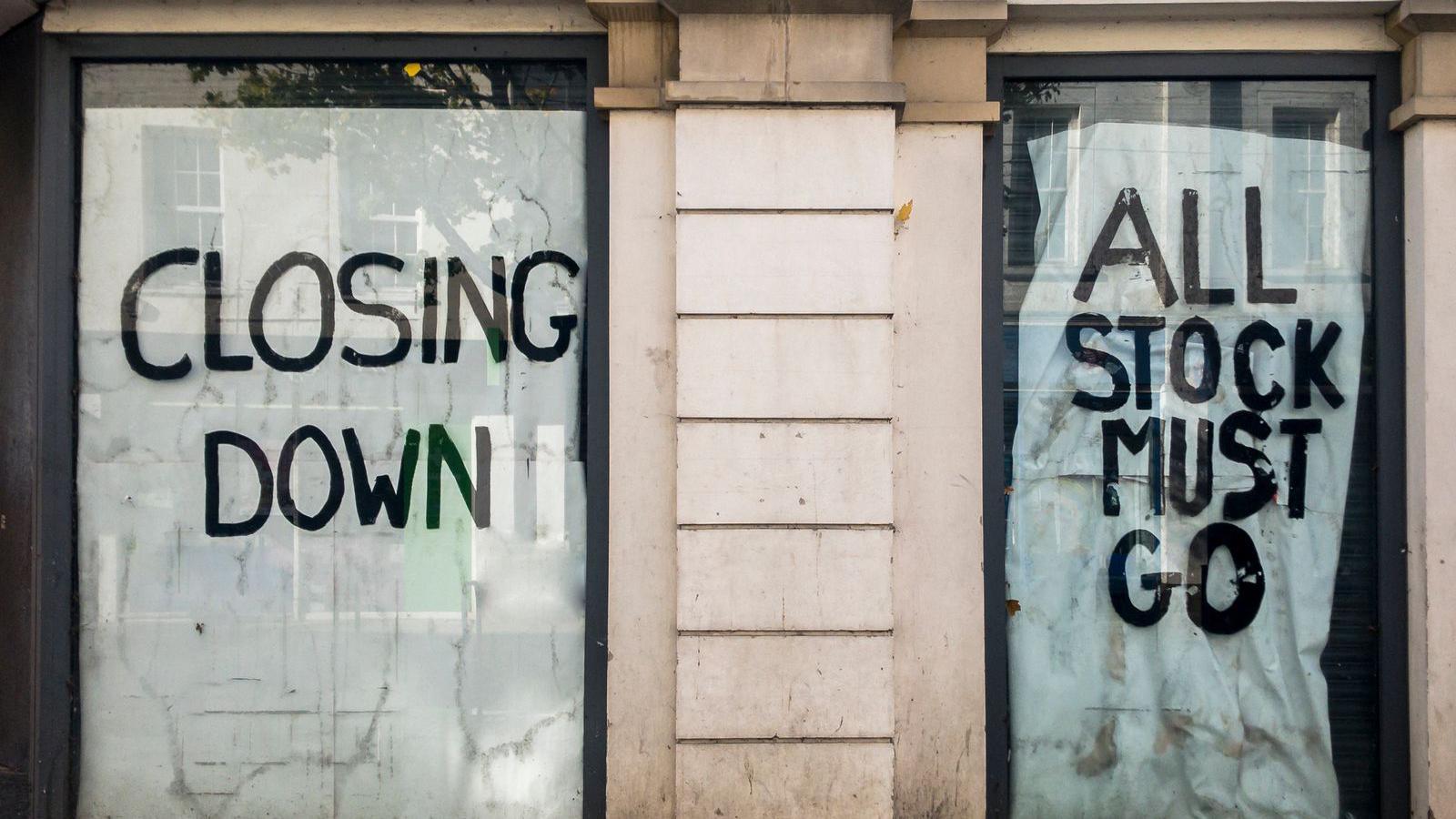 Shop windows with signs in saying Closing Down and All Stock Must Go in capital letters