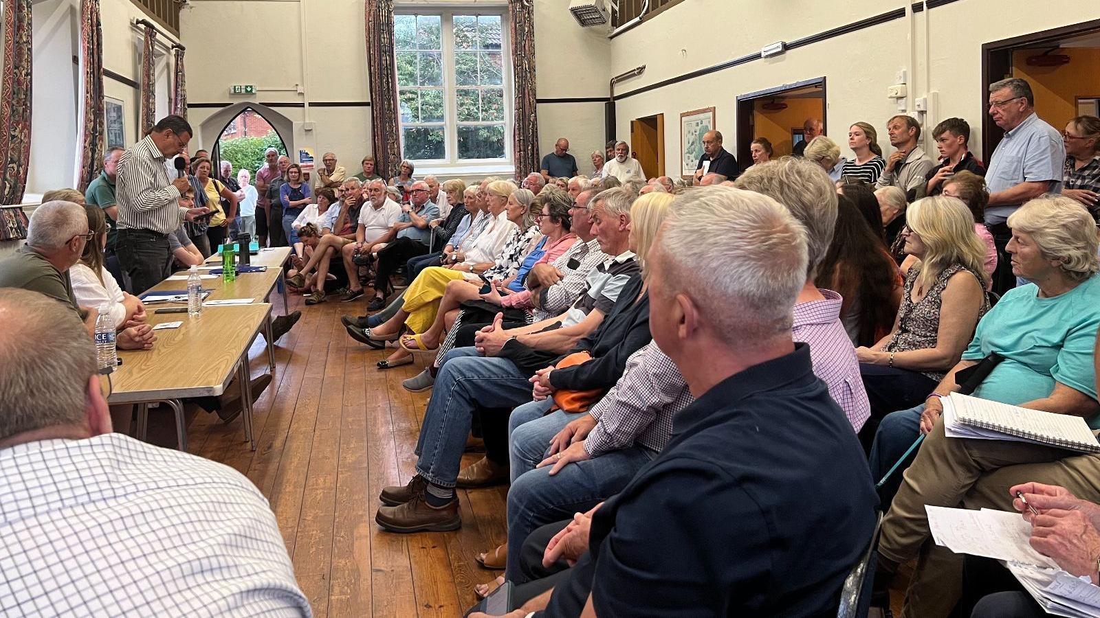 A village hall full of people at the Redmarley Parish Council meeting.