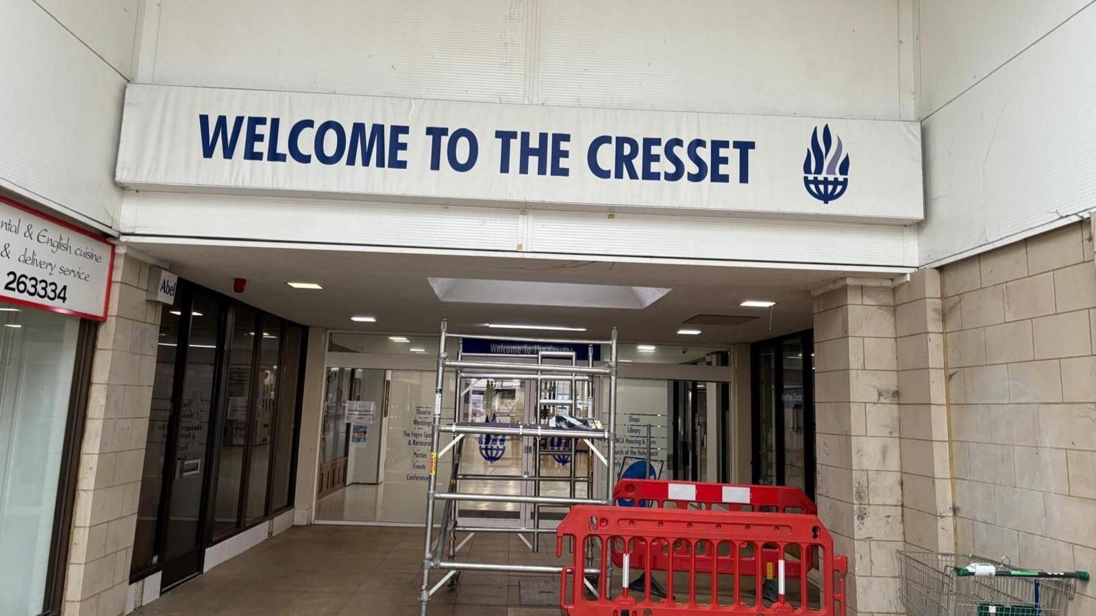 The entrance to the Cresset - a white board with blue writing - and some metal scaffolding in front of it.