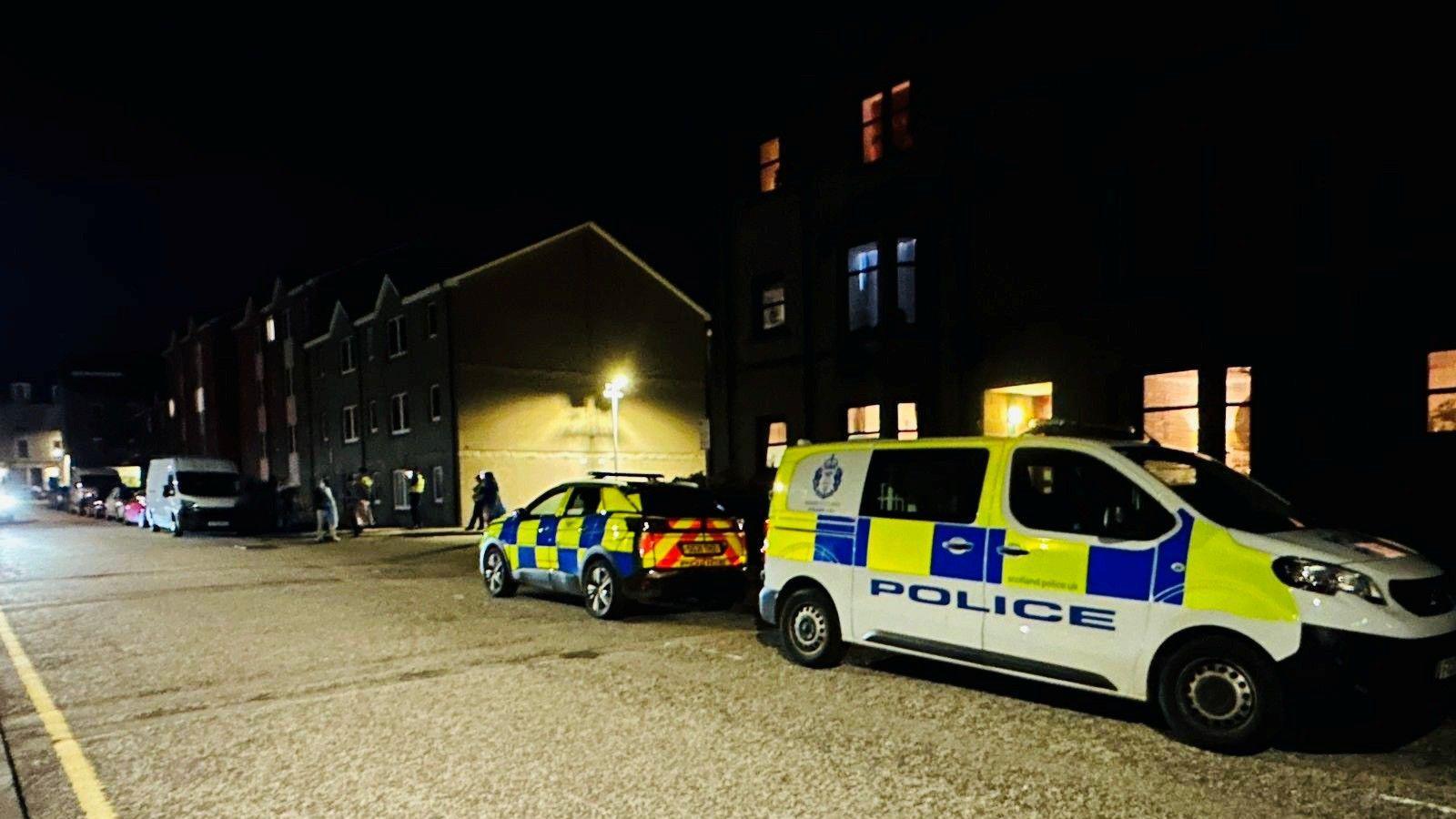 Police vehicles outside Farmer's Hall in Aberdeen, in the dark.