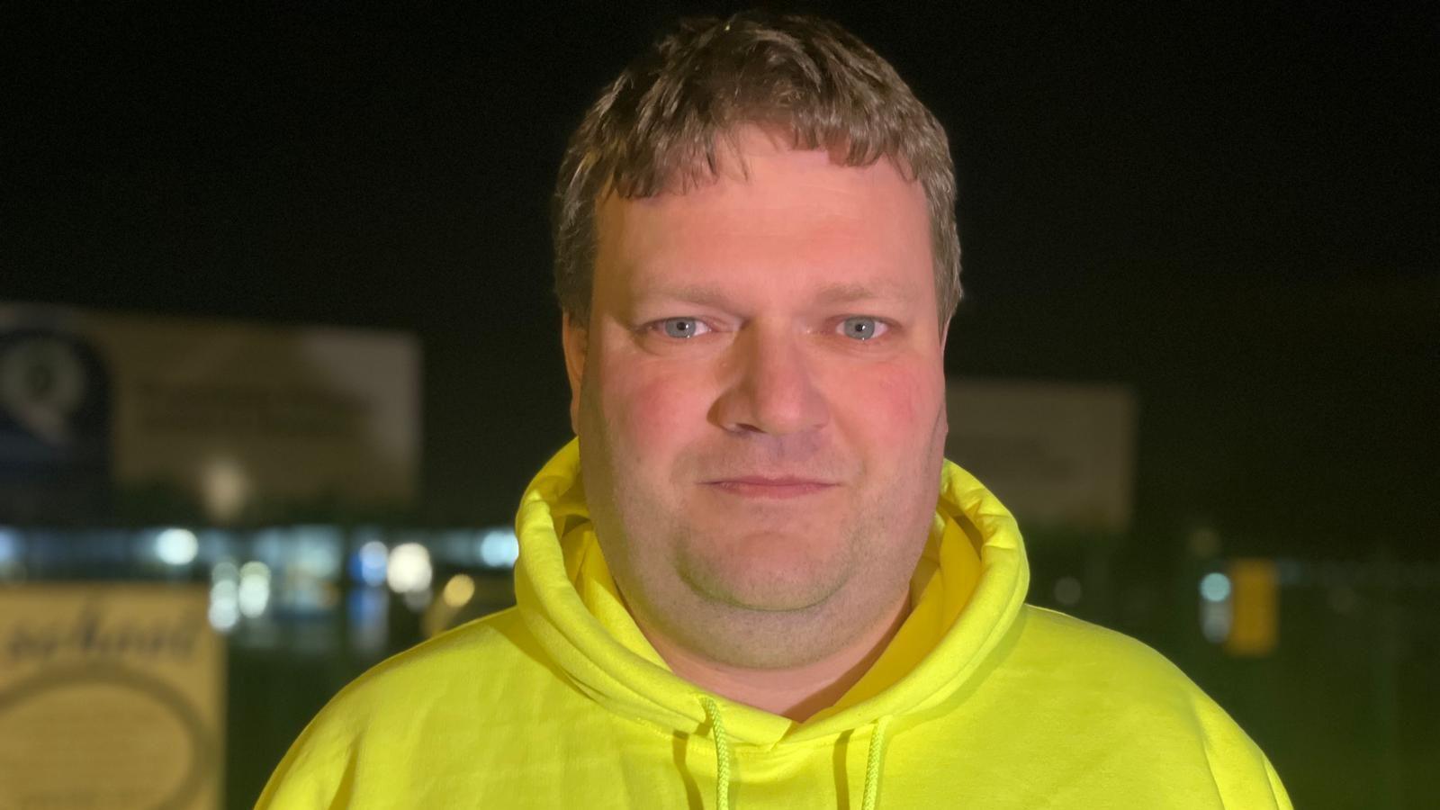 Parent Matt Ford wears a bright yellow "save our school again" hoodie.