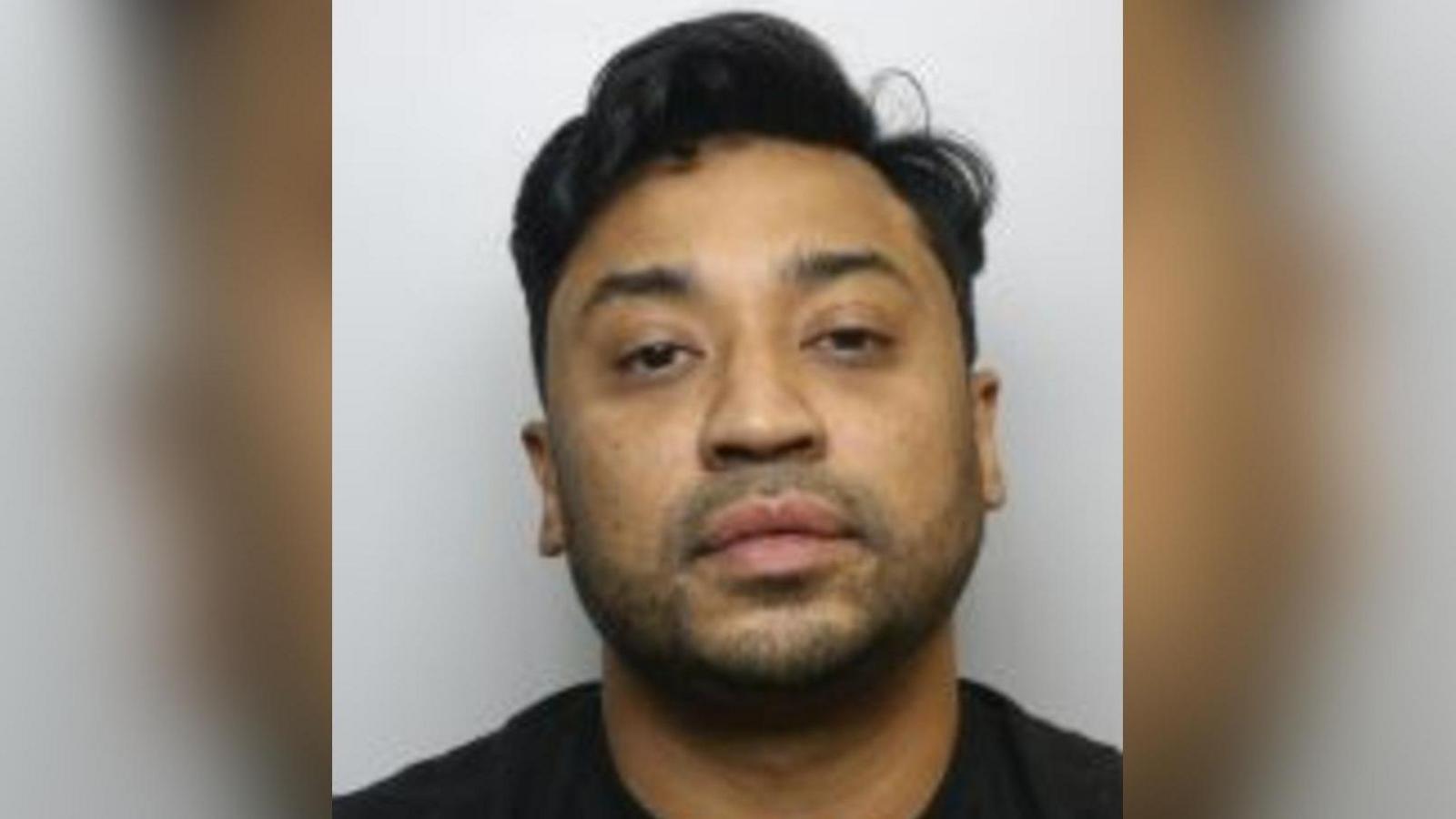 A police mugshot of Shafiqul Islam Ali. He has dark hair and stubble and is wearing a black jumper.