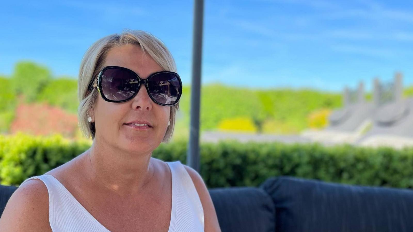 A woman in shades sat in her garden