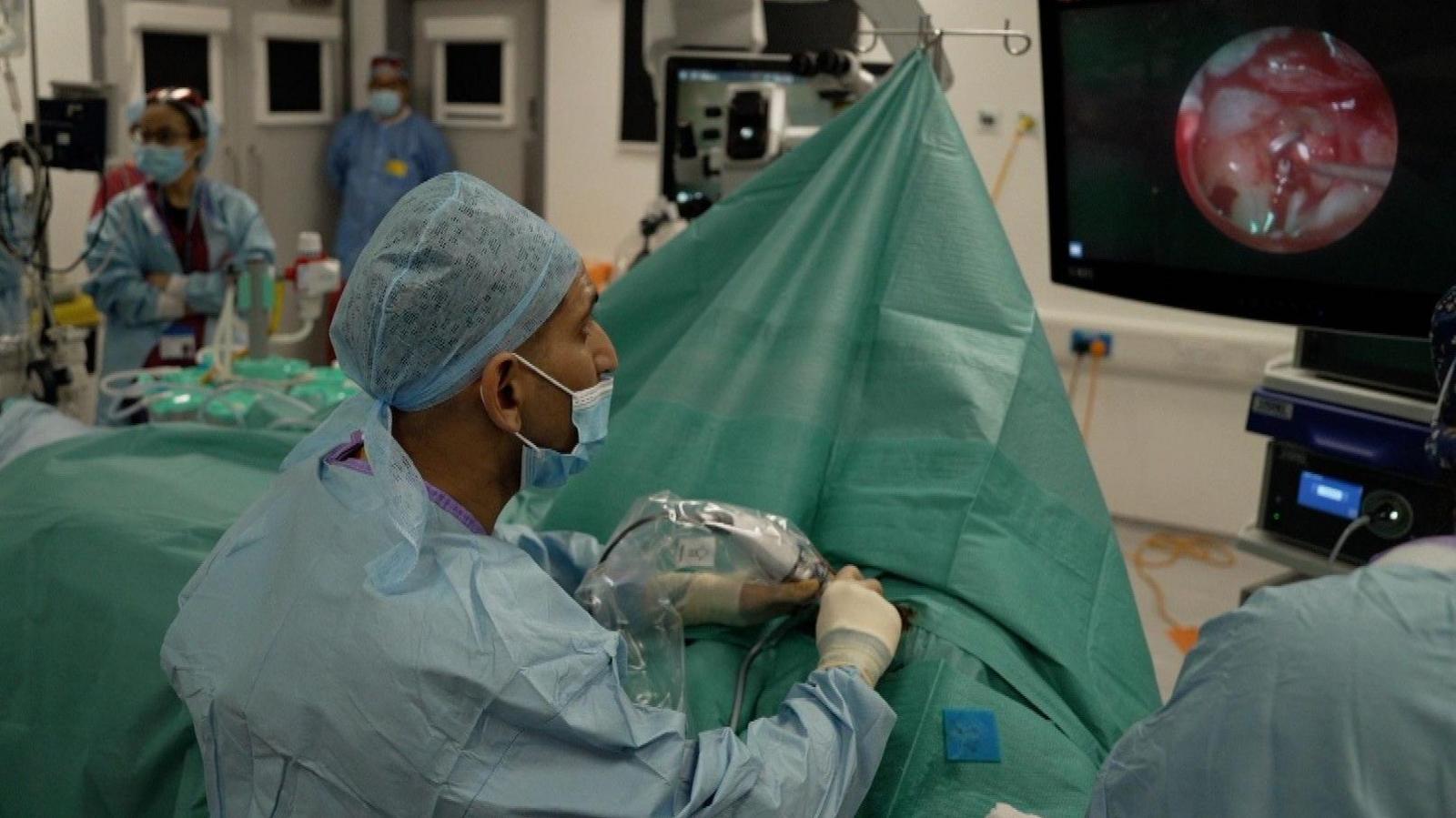 Surgeon operating with a big screen in an operating theatre.