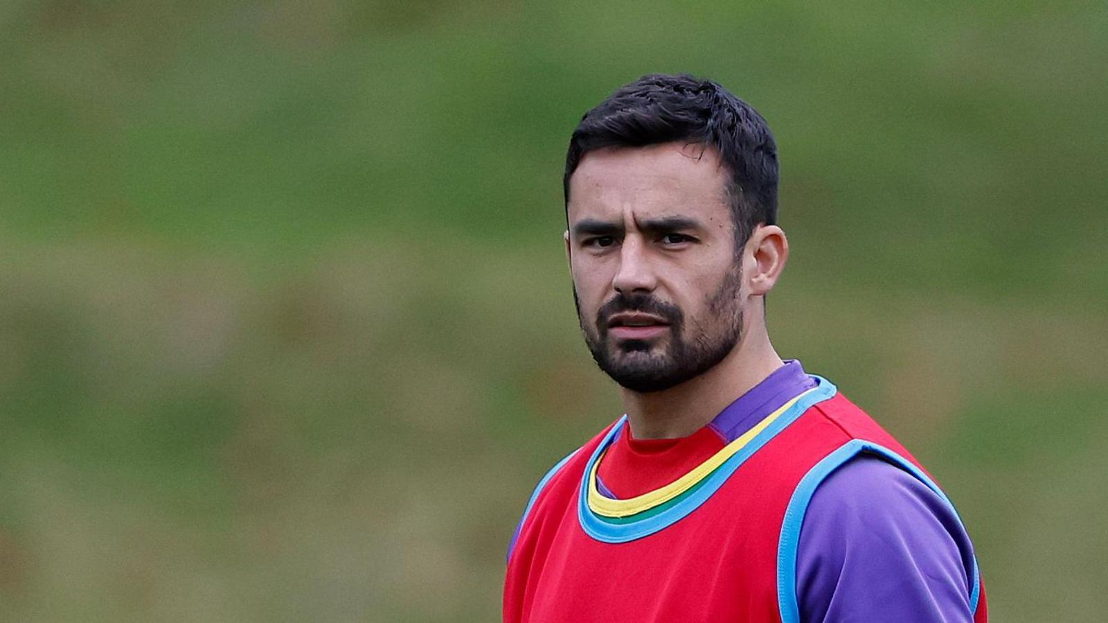 Alex Lozowski wearing a purple top and a red bib on training duty with England 