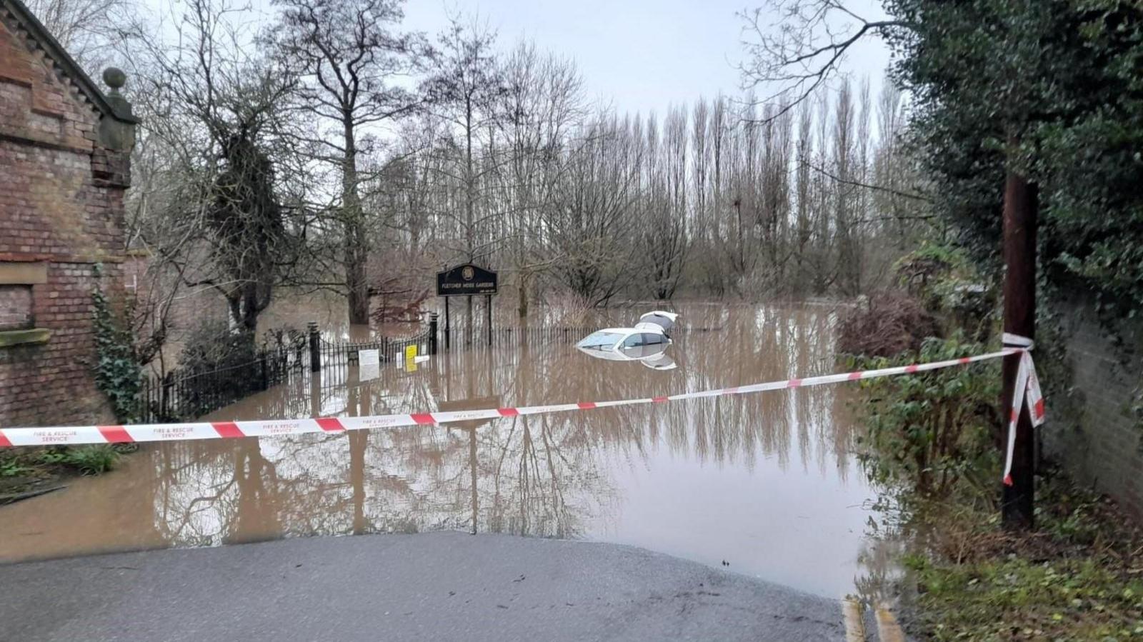 A car is almost fully submerged in a park area 