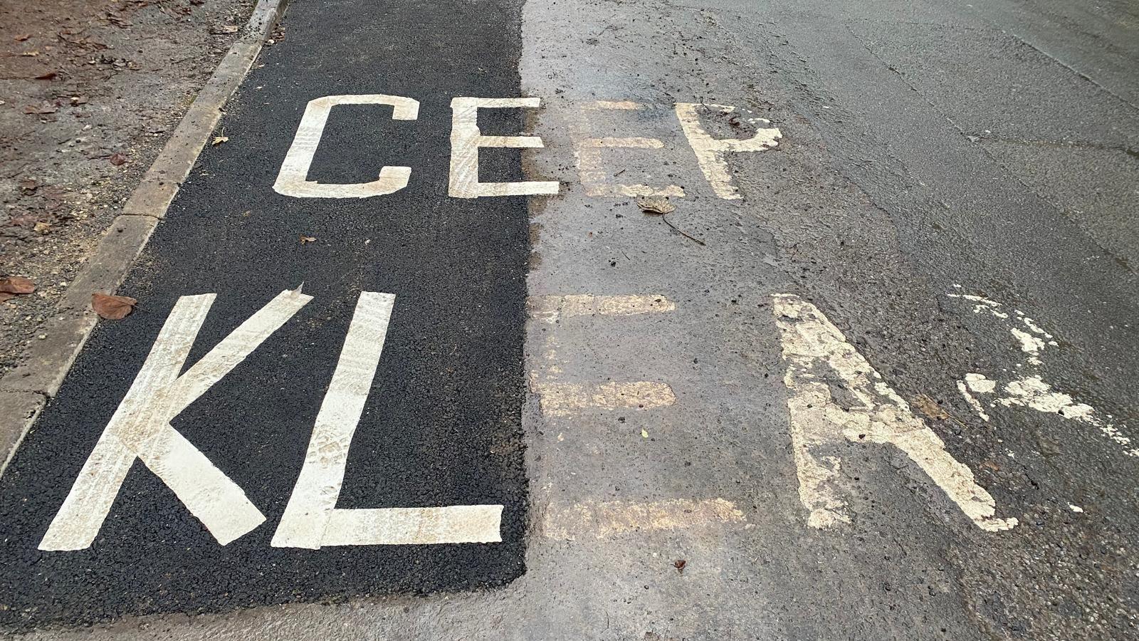 A stretch of newly-patched road covering a "Keep Clear" marking on the road. The repainted marking read "Ceep Klear" with C and K the wrong way around.