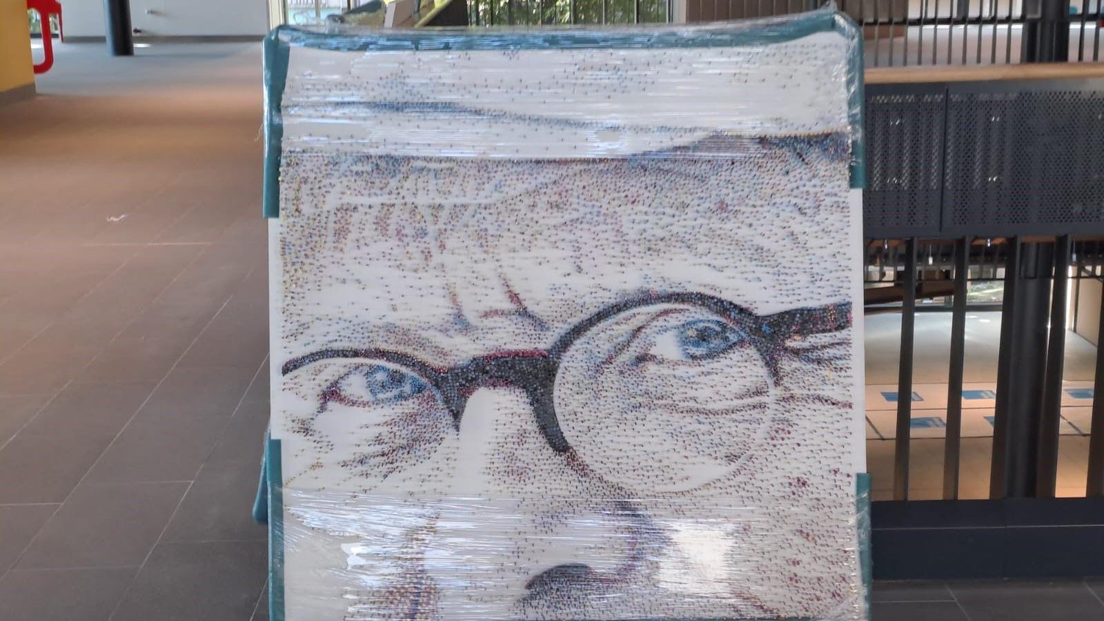 One square of the David Hockney portrait featuring a close-up of the painter's bespectacled face, standing against some railings