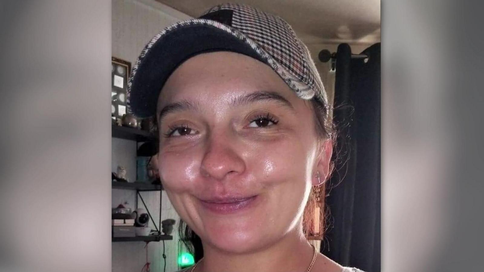 Woman smiling with a patterned baseball cap on and hair tied back 