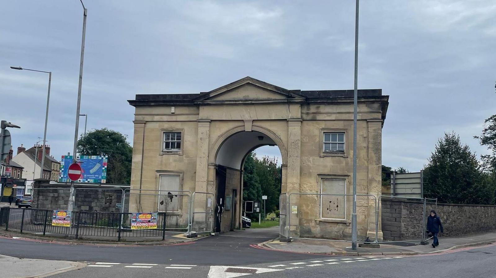 Roadside view of the front of the two-storey arch, with four windows, two of which are blocked out