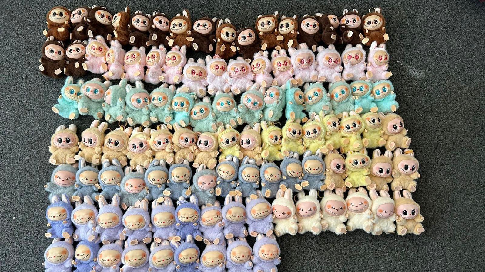 Dozens of fake Labubu dolls lined up in a variety of colours.