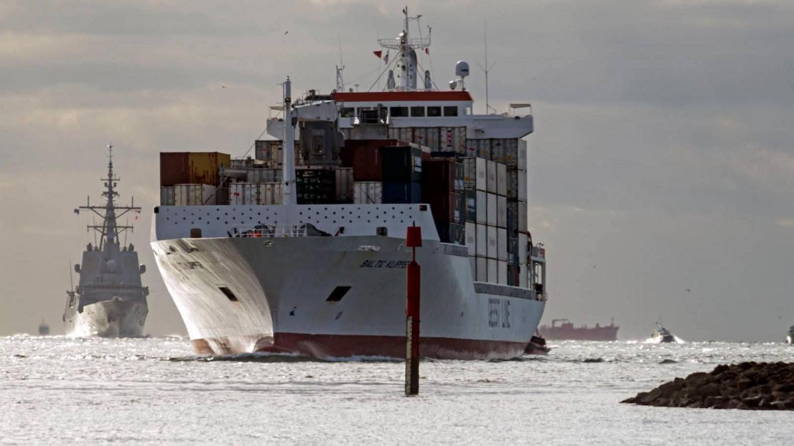 A large white cargo ship loaded with metal boxes.