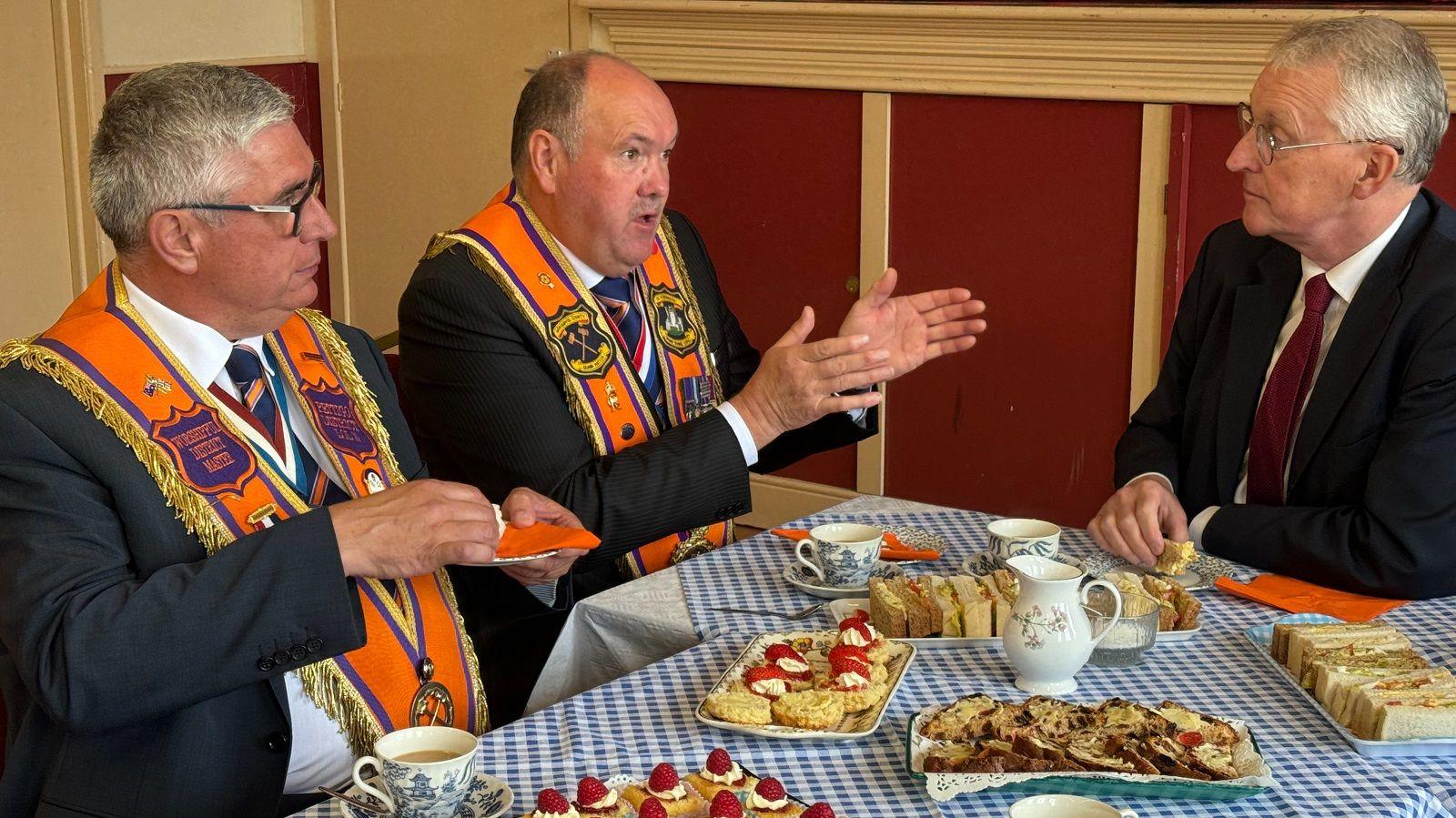  Hilary Benn with two Orangemen with some scones and sandwiches 