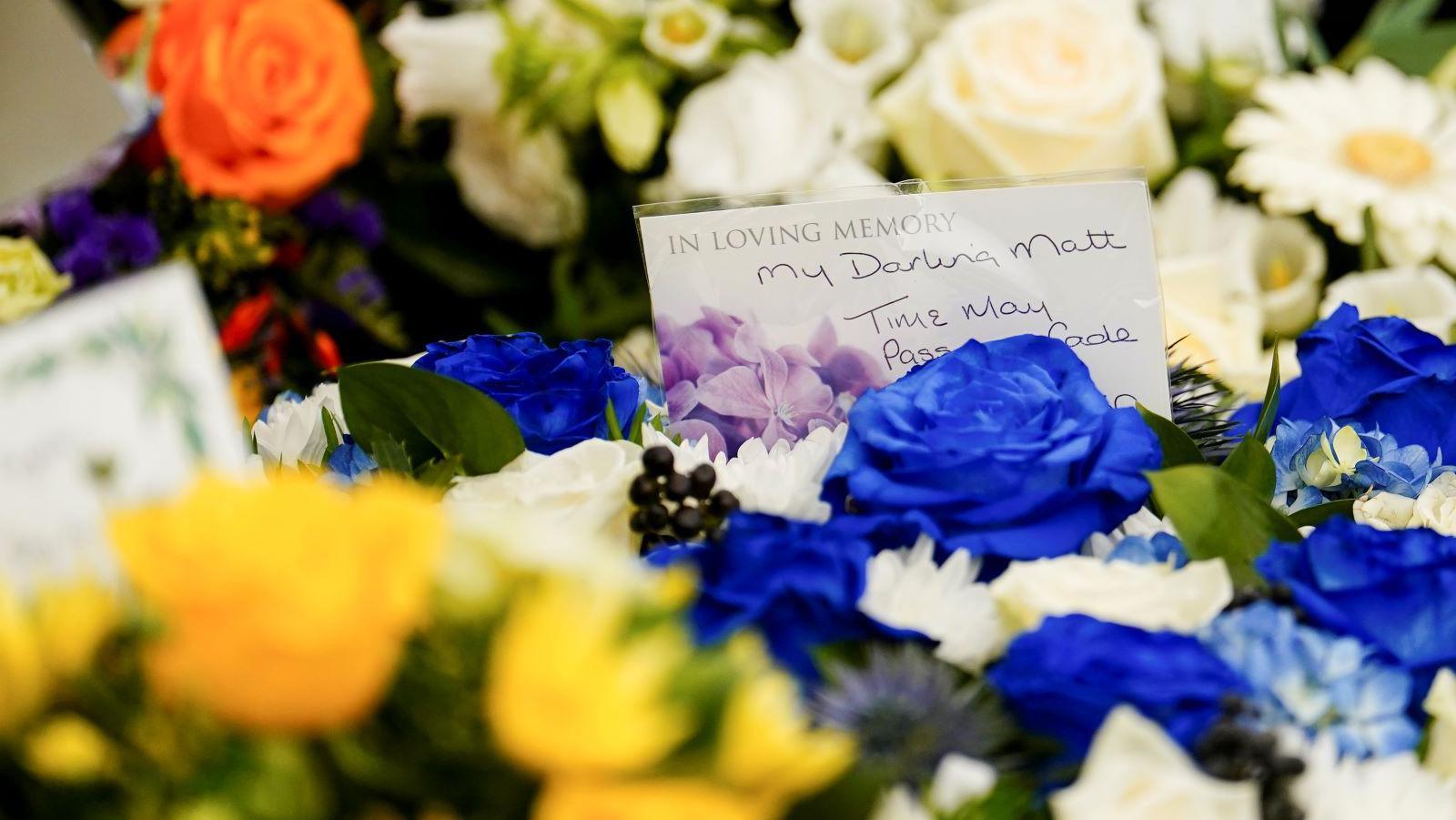 Message of condolence on blue and yellow flower wreath 