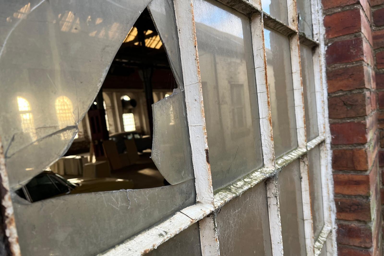 The inside of the warehouse can be seen through a broken pane of glass.